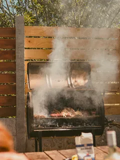Person grilling food outdoors on a barbecue grill