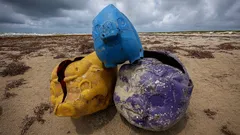 Colorful plastic debris on sandy beach under cloudy sky