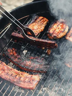 Delicious grilled meat cooking on a black charcoal barbecue grill